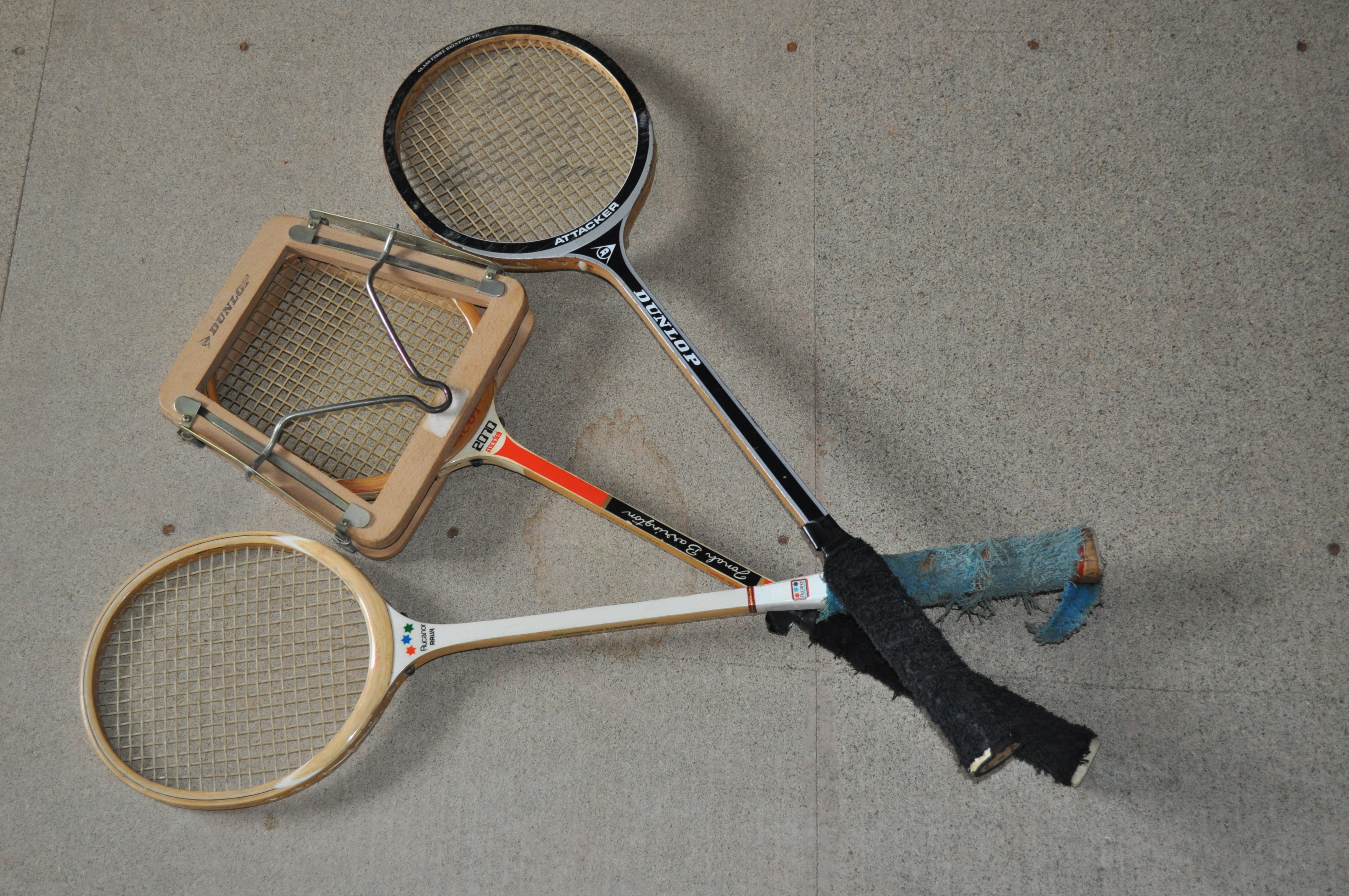 Three wooden rackets, one with racket press